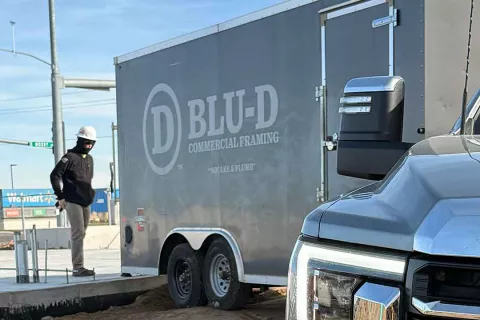 BLU-D Commercial Framing trailer with "Square & Plumb" tagline parked at the AFCU Rexburg job site