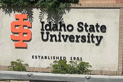 Idaho State University monument sign with the orange "ISU" mark and "Established 1901" lettering on a weathered concrete wall