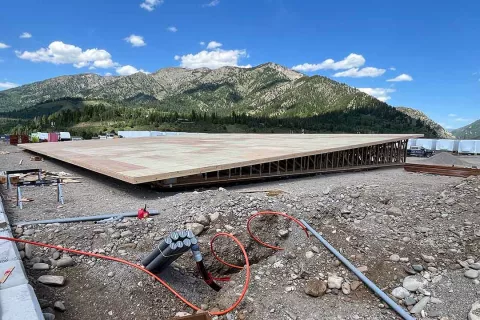 Completed wood deck system at the Alpine Hotel built atop engineered floor trusses, with electrical conduit staged in the foreground and the Snake River Range behind