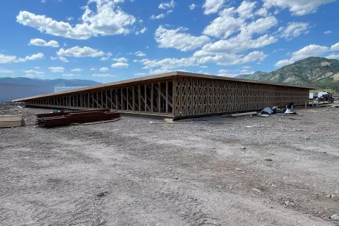Long view of the Alpine Hotel's truss-framed wall assembly extending across the building footprint under partly cloudy skies