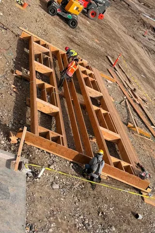 View through wood framing at an upper level of Grand Peaks looking down into the building's courtyard, with framed walls and tarped material below