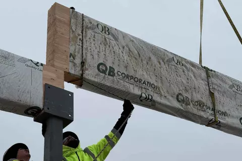 BLU-D framer guiding a packaged glulam beam from QB Corporation as it lands on a steel column cap at Grand Peaks