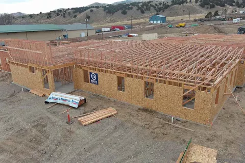 Completed exterior framing and roof truss installation on IDOC Re-entry Center building with mountain backdrop