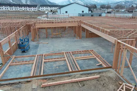 Interior framing with roof trusses and partition walls at IDOC Re-entry Center, mountains and housing in distance