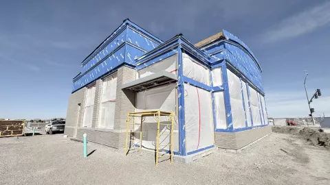 Blue sky behind a vapor wrapped building.