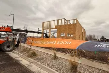 "New Branch Coming Soon" banner at the AFCU Rexburg project site, with the wood-framed building shell visible behind the construction fence