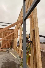 Detail of wood-to-steel framing connection at AFCU Rexburg — engineered lumber tied into a steel column with a man-lift in the background