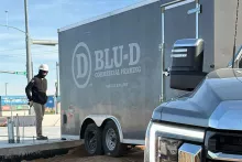 BLU-D Commercial Framing trailer with "Square & Plumb" tagline parked at the AFCU Rexburg job site