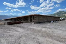Long view of the Alpine Hotel's truss-framed wall assembly extending across the building footprint under partly cloudy skies