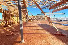 Wide interior view at Grand Peaks showing diagonal lateral bracing, steel columns, OSB-sheathed walls, and roof framing extending toward the horizon