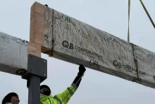 BLU-D framer guiding a packaged glulam beam from QB Corporation as it lands on a steel column cap at Grand Peaks
