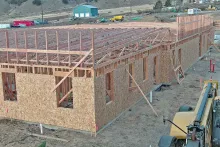 Exterior wall framing and roof trusses installed on IDOC Re-entry Center building with OSB sheathing