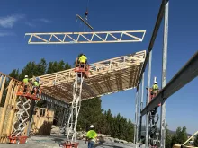 A roof truss lifted into place at the Island Park Adventure Lodge, the crew on scissor lifts