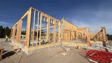 Exterior walls framed on the slab at the Island Park Adventure Lodge, blue sky behind