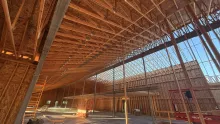Inside the Island Park Adventure Lodge: roof trusses over the wood-framed hall and its tall window wall