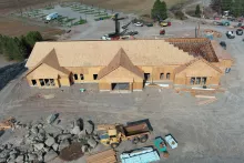 Aerial view over the Island Park Adventure Lodge site, the sheathed roof with its last trusses being set