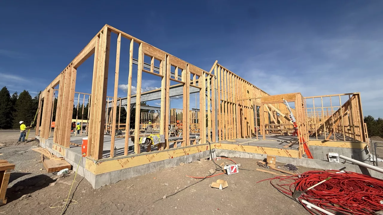 Exterior walls framed on the slab at the Island Park Adventure Lodge, blue sky behind