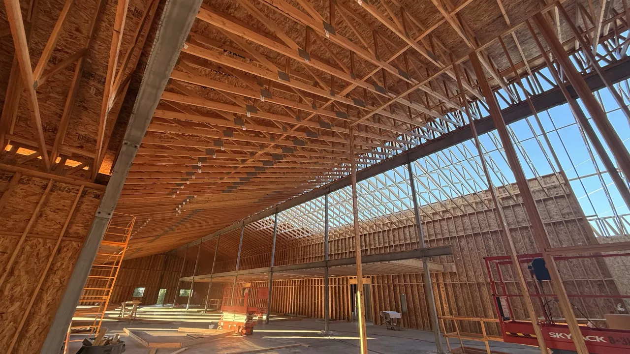 Inside the Island Park Adventure Lodge: roof trusses over the wood-framed hall and its tall window wall
