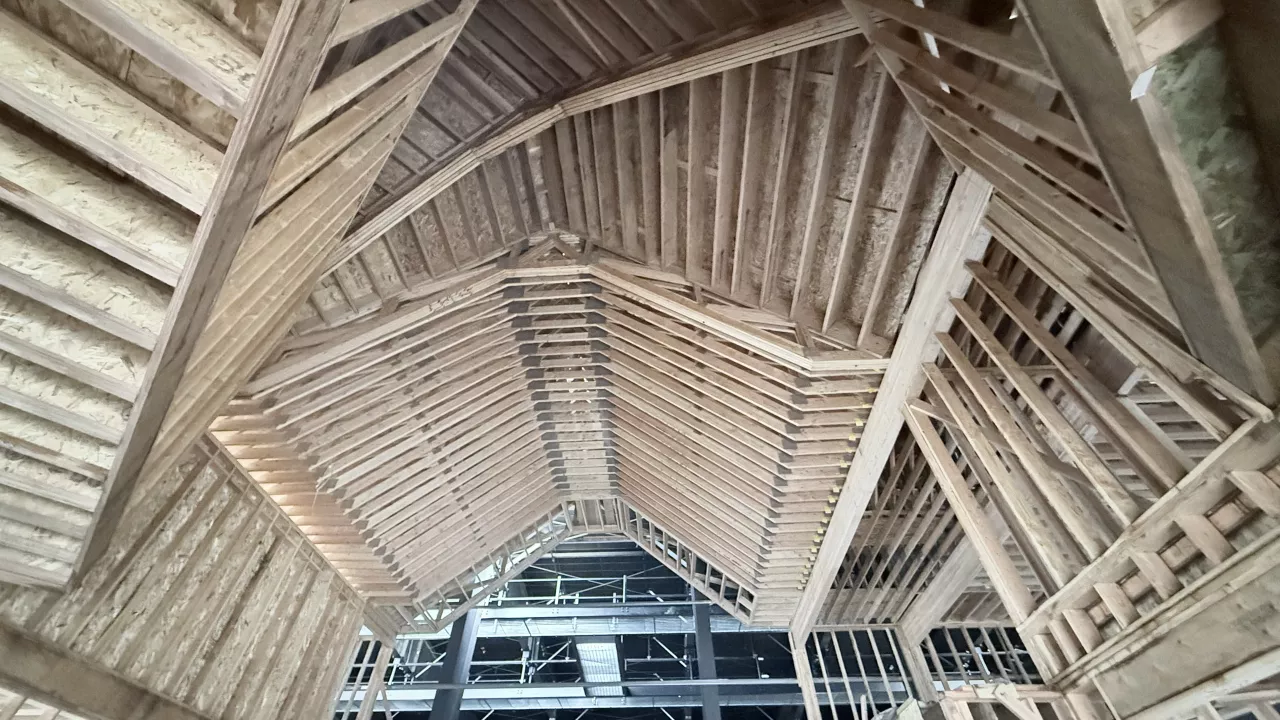 Looking up into the Playmill Theater's vaulted roof framing, rafters meeting at the peak