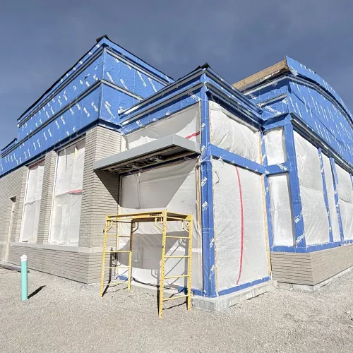 Blue sky behind a vapor wrapped building.